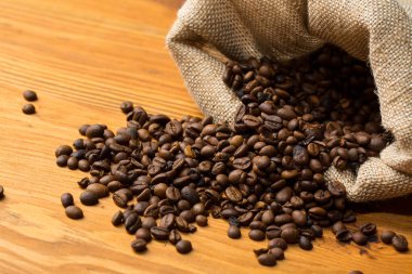 Ahşap arka planda kahve çekirdekleri olan çanta.