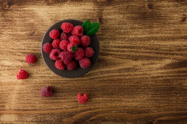 Himbeeren in Schale auf Holztisch — Stockfoto