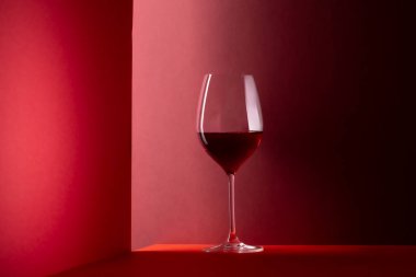 Kırmızı arkaplanda kırmızı şarap kadehi ve kopyalama alanı