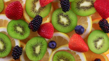 Meyve salatası süsü. Çember şeklinde sunulan farklı meyvelerden oluşan bir tabağın dönüşümlü görüntüsü..