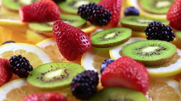 Meyve salatası süsü. Çember şeklinde sunulan farklı meyvelerden oluşan bir tabağın dönüşümlü görüntüsü..