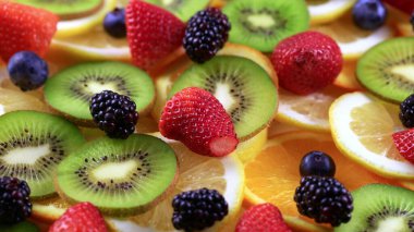 Meyve salatası süsü. Çember şeklinde sunulan farklı meyvelerden oluşan bir tabağın dönüşümlü görüntüsü..