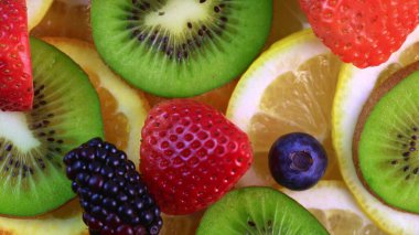 Meyve salatası süsü. Çember şeklinde sunulan farklı meyvelerden oluşan bir tabağın dönüşümlü görüntüsü..