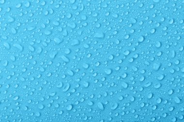 Su damlacıkları açık mavi bir yüzey üzerinde toplanarak, açık bir yoğunlaşma manzarası gösterirler. Sahne, ışığın altında parlayan küçük damlaları yakalar..