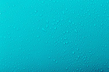 Su damlacıkları pürüzsüz bir yüzeyde, çeşitli boyutlarda bulunurlar. Arka plan koyu mavi renkte, serin bir atmosfer olduğunu gösteriyor. Damlacıklardan yansıyan ışık.