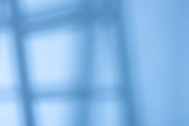 Mavi arka plan bulanık çizgileri ve güneş ışığının gölgelerini gösteriyor. İçerisi kapalı gibi görünüyor. Gündüz vakti modern bir yapı izlenimi veriyor..