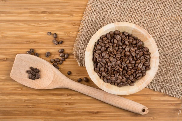 Granos de café en tazón sobre fondo de madera — Foto de Stock