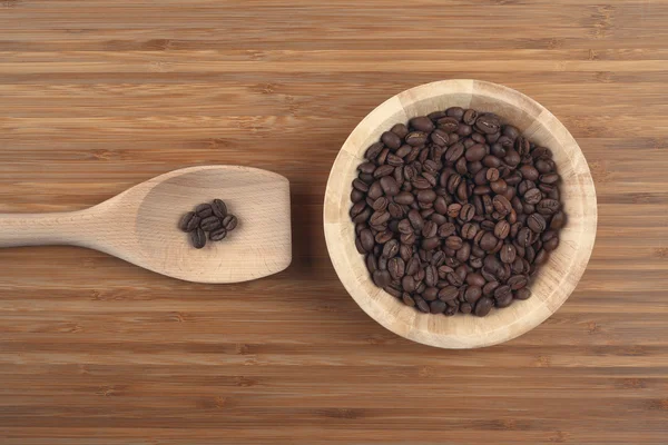 Granos de café en tazón sobre fondo de madera —  Fotos de Stock