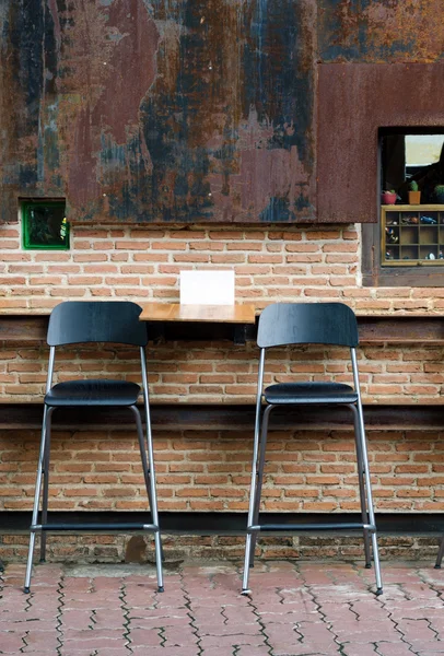 Two cafe chairs against brick wall — Stock Photo, Image