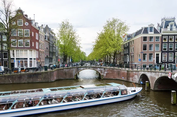 Amsterdam, Países Bajos - 7 de mayo de 2015: Pasajeros en barco por el canal en la ciudad de Amsterdam . — Foto de Stock