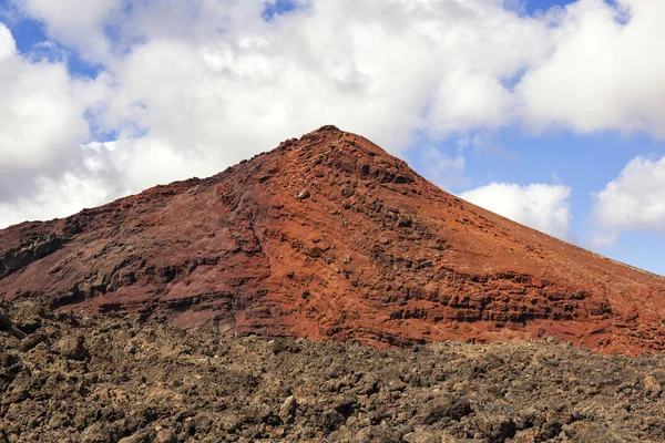 Röda vulkan med stelnad lava i förgrunden — Stockfoto
