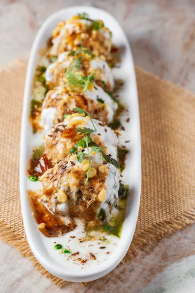 Chaat Dahi Vada (diğer adıyla Dahi Bhalla, Doi Bora, mosaru vade, Dahi Bara, thayir vadai, perugu vada). Vadas 'ın yoğun yoğurda batırılmasıyla hazırlanıyor. Kimyon ve yeşil kişniş ile süslenmiş.