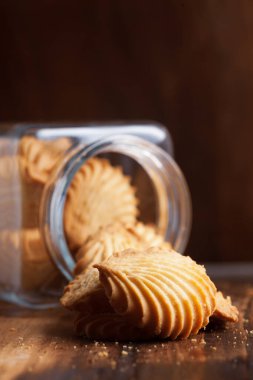 Cam kavanozdan yeni pişmiş lezzetli kurabiyeler ya da bisküviler çıkıyor. ahşap bir arkaplan üzerinde.