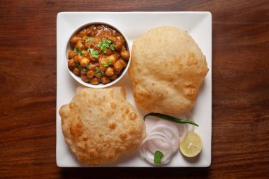 Nohut masala (baharatlı chola veya chhole curry) ve taze yeşil kişniş ve malzemelerle süslenmiş Bhatura veya Puri. Klasik bir Hint yemeği. Tipik Panjabi sokak yemeği..