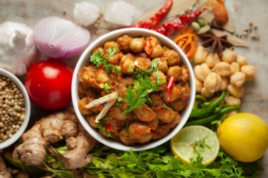 Taze yeşil kişniş ve malzemelerle süslenmiş nohut masalası (baharatlı köri veya chole). Beyaz seramik kasede servis ediliyor. Klasik Hint yemeği. Tipik Panjabi sokak yemeği. Siyah granit kaplamalı.