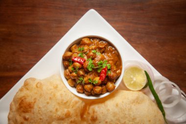 Nohut masala (baharatlı chola veya chhole curry) ve taze yeşil kişniş ve malzemelerle süslenmiş Bhatura veya Puri. Klasik bir Hint yemeği. Tipik Panjabi sokak yemeği..