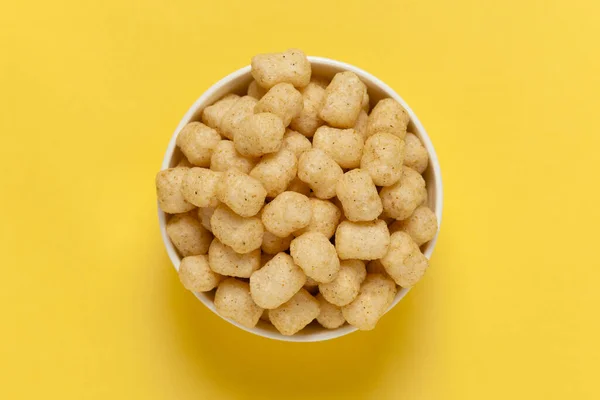 Close up of Cheese Potato Puff Snacks ball and buds, Popular Ready to eat crunchy and puffed snacks buds, cheesy salty pale-yellow color over yellow background