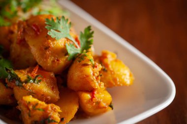 Hint usulü vejetaryen baharatlı patates ve körili yeşil kişniş yapraklarıyla süslenmiş domates yemeği..