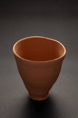Boş Hint Eli 'nin yakın çekimi, Clay Red Pot' u (kulhad) siyah arka planda parlatılmamış hale getirdi.