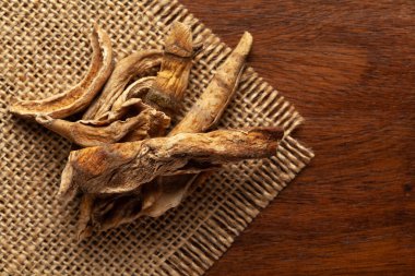 Organik kurutulmuş mango dilimleri (Mangifera indica) ya da ahşap arka plan ve jute mat üzerinde amchoor yakın plan. Hint Aromatik Baharatı Yığını. Üst görünüm