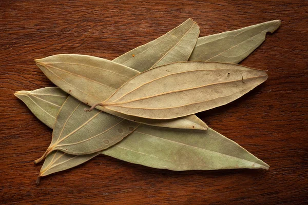 Tahta arka planda organik Hint defne yaprağı (Cinnamomum tamala) tezpatta 'nın Macro yakın çekimi. Hint Aromatik Baharatı Yığını. Üst görünüm