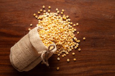 Organik arhar dalına (Cajanus cajan) yakın plan veya tahtadan yapılmış kahverengi arka plan üzerine döşeme jüt çantasından dökülen sarı dal.