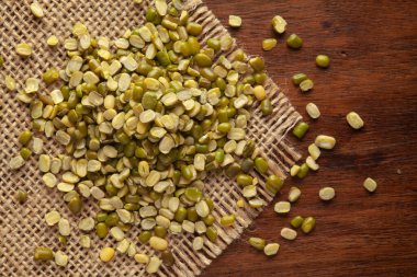 Organik bölünmüş ve cilalanmamış yeşil Moong Dal 'ın (Vigna radyatör) Jute minder ve ahşap tepeye yakın çekimi.