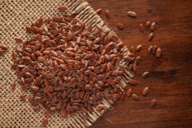 Macro Organik Kahverengi keten tohumlarına (Linum usitatissimum) ya da Jute minderinde temizlenmiş keten tohumu ve ahşap üst.