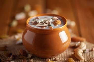 Kuru meyvelerle süslenmiş kremalı Sabudana Kheer 'in yakın çekimi. Hint usulü lezzetli tatlı. Toprak tencerede servis edilmiş. Ahşap arkaplanda Üst Görünüm.