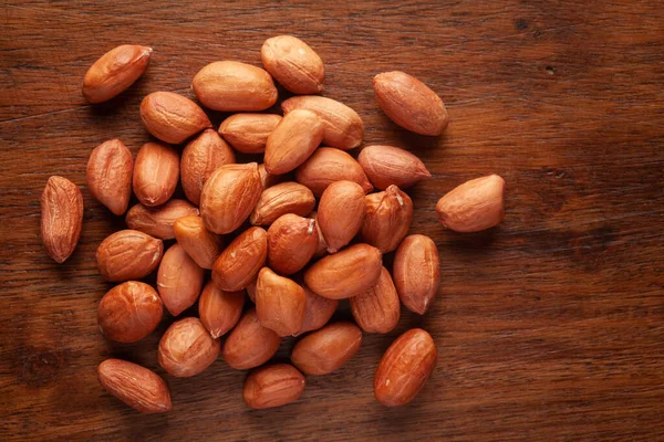 Macro Close up of organic red brown peanuts (Arachis hypogaea) cleaned on wooden top background.