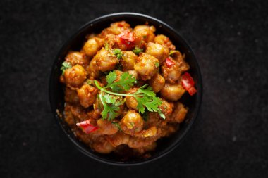 Taze yeşil kişniş ve malzemelerle süslenmiş nohut masalası (baharatlı köri veya chole). Siyah bir kasede servis edilmiş. Klasik bir Hint yemeği. Tipik Panjabi sokak yemeği..