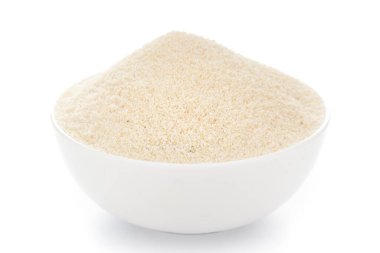 Beyaz arkaplan üzerinde beyaz seramik kâse içinde organik irmik granüllerin yakın çekimi