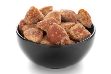 Beyaz zemin üzerinde siyah seramik kâse içinde organik şeker kamışı jaggery parça yakın plan