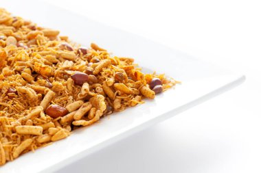 Fıstık, mısır gevreği vs. ile yapılmış beyaz seramik kare tabakta baharatlı chatpata karışımı. Hindistan baharatlı çerez yığını (Namkeen), arka plan ışığı altında, yan görünüm, beyaz arka plan karşı.