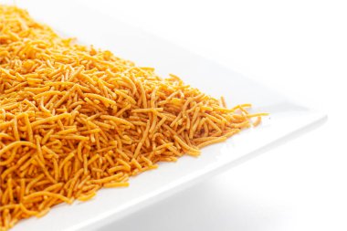 Kırmızı biber, patates ve nohut ile yapılan beyaz seramik kare tabakta baharatlı Aloo Bhujia. Hindistan baharatlı çerez yığını (Namkeen), arka plan ışığı altında, yan görünüm, beyaz arka plan karşı.