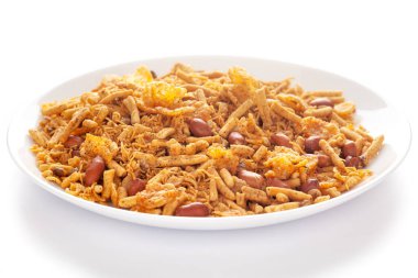 Fıstık, mısır gevreği vs. ile yapılmış beyaz seramik bir tabakta baharatlı chatpata karışımı. Hindistan baharatlı çerez yığını (Namkeen), arka plan ışığı altında, yan görüş,