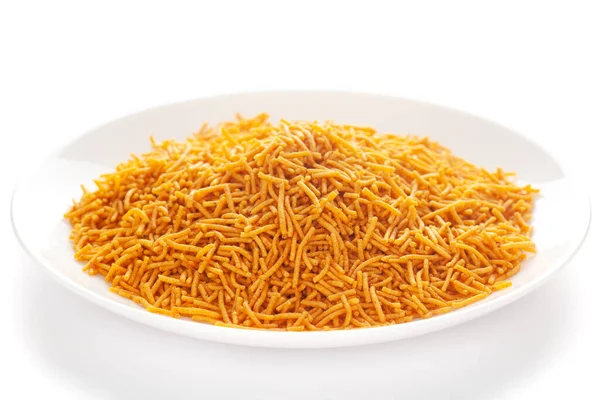 Kırmızı biber, patates ve nohut ile yapılan beyaz seramik tabakta baharatlı Aloo Bhujia. Hindistan baharatlı çerez yığını (Namkeen), arka plan ışığı altında, yan görüş