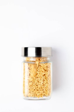 Hint baharatlı aperatifleri (Namkeen) - Bikaneri Besan Bhujia cam bir kavanozda, nohut unundan (Besan) yapılmış, beyaz arka plan üzerinde üst görünüm.