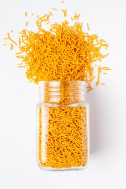 Baharatlı Aloo Bhujia, kırmızı biber, patates ve nohuttan yapılmış cam bir kavanoza döküldü. Hint baharatlı çerezleri (Namkeen), Üst Manzara, beyaz arka plan üzerinde.