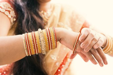 Düğün sırasında geleneksel altın bilezikler takan Hintli bir gelinin güzel elleri.