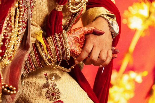 An Indian bride and groom holding their hands during a Hindu wedding ritual. Close up view, selective focus.