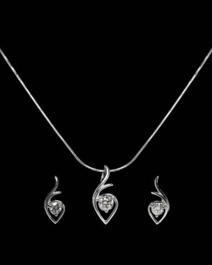 Siyah arkaplanda elmas küpeli elmas kolyeyi kapat.