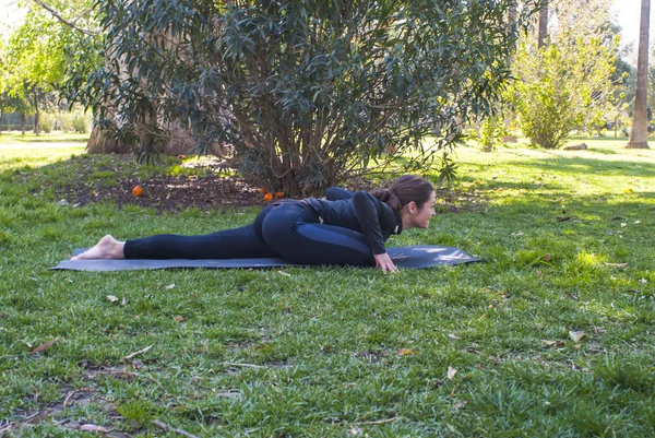 Mulher bonita praticando ioga no parque em um dia ensolarado — Fotografia de Stock