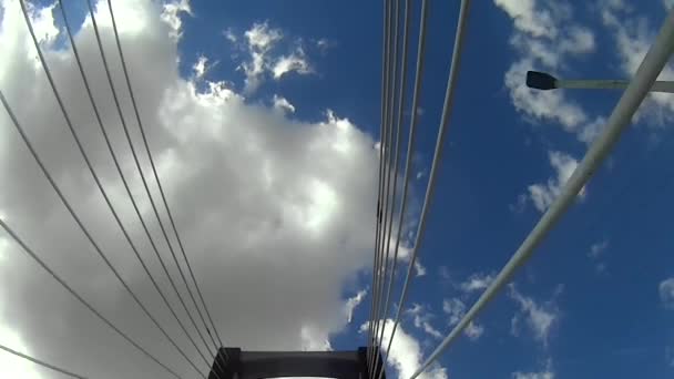 Vista inferior de uma ponte enquanto cruza com céu azul e nuvens brancas — Vídeo de Stock