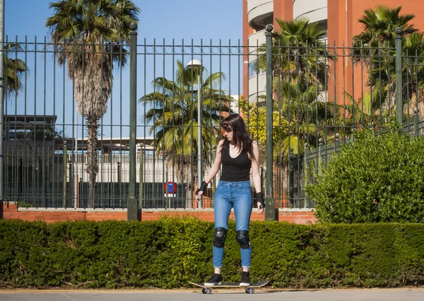 Vacker ung kvinna tränar med skateboard på stre — Stockfoto