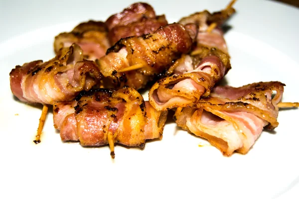 Rullar av skivor av kokta bacon ämne med en tandpetare på en wh — Stockfoto