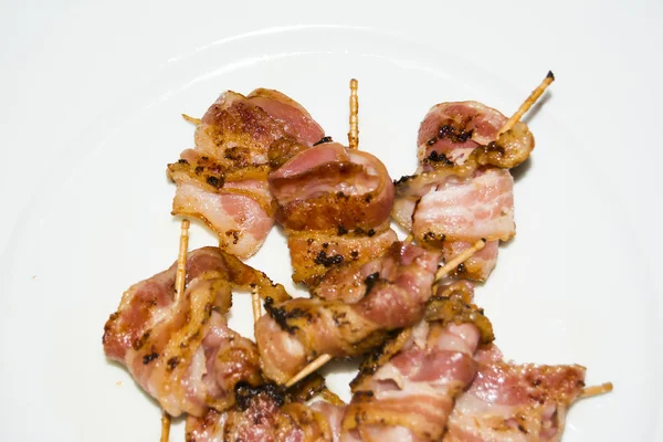 Rollos de rodajas de tocino cocido sujeto con un palillo — Foto de Stock