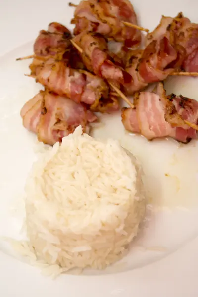 Arroz con rollos de rodajas de tocino cocido sujeto con un toothpi — Foto de Stock