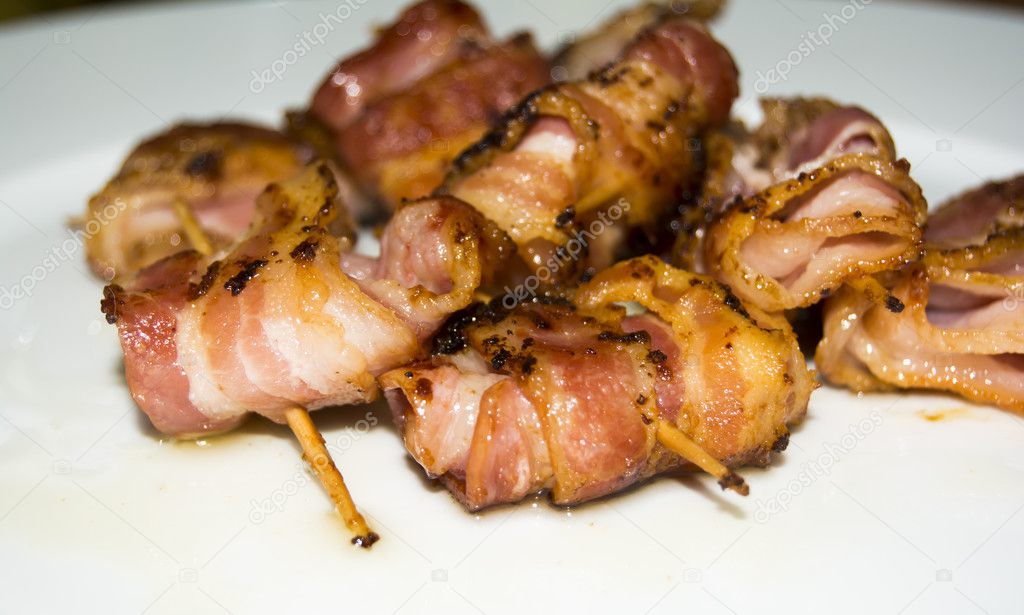 Rolls of slices of cooked bacon subject with a toothpick 