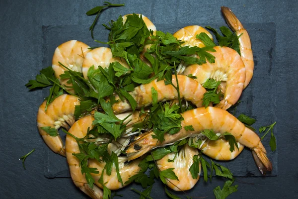 Camarones con perejil sobre pizarra de piedra — Foto de Stock